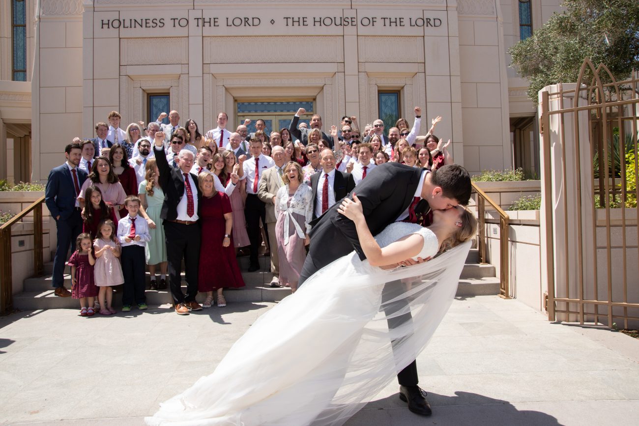 Bride and groom photo on the Gilbert Temple steps with family watching