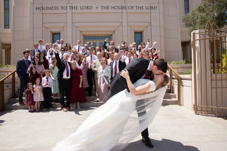 Bride and groom photo on the Gilbert Temple steps with family watching