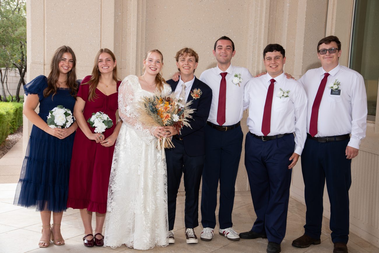 Bride and groom posing with their bridal party outside the Phoenix Arizona Temple after their wedding ceremony.