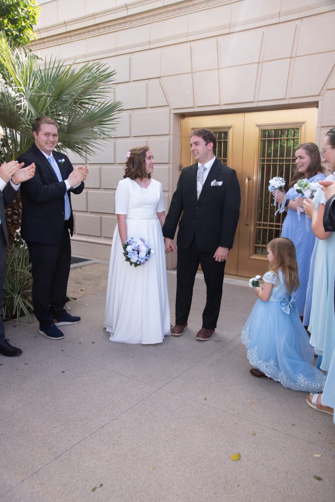 Bride and groom exit the Mesa Temple on the East side surrounded by family.
