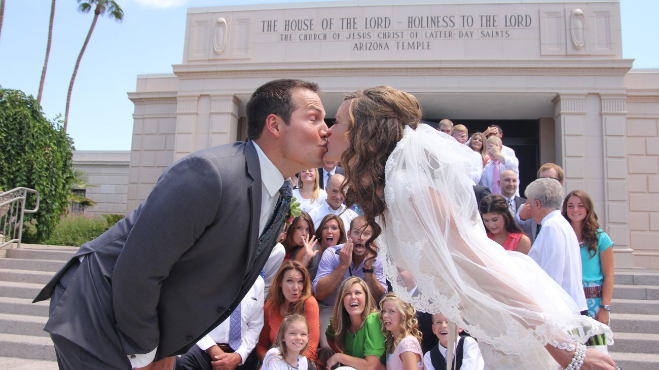 Bride and groom lean in the middle and kiss after the wedding at the Mesa Arizona Temple.