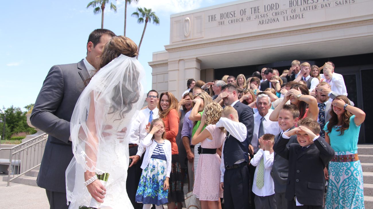 Bride and groom on temple steps at the Mesa Arizona Temple kissing.