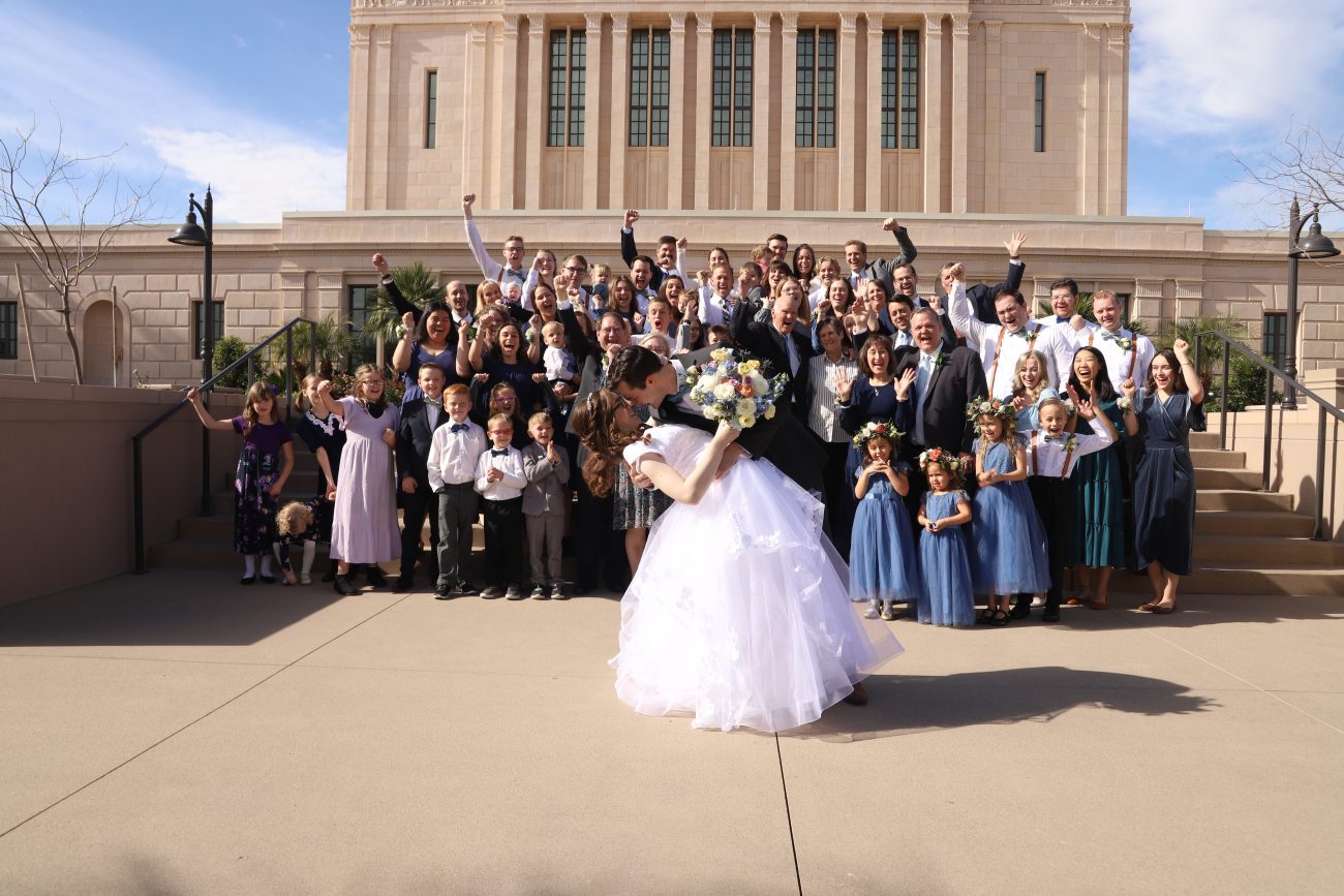 Bride and groom kissing at the Mesa Arizona Temple for large family photo.