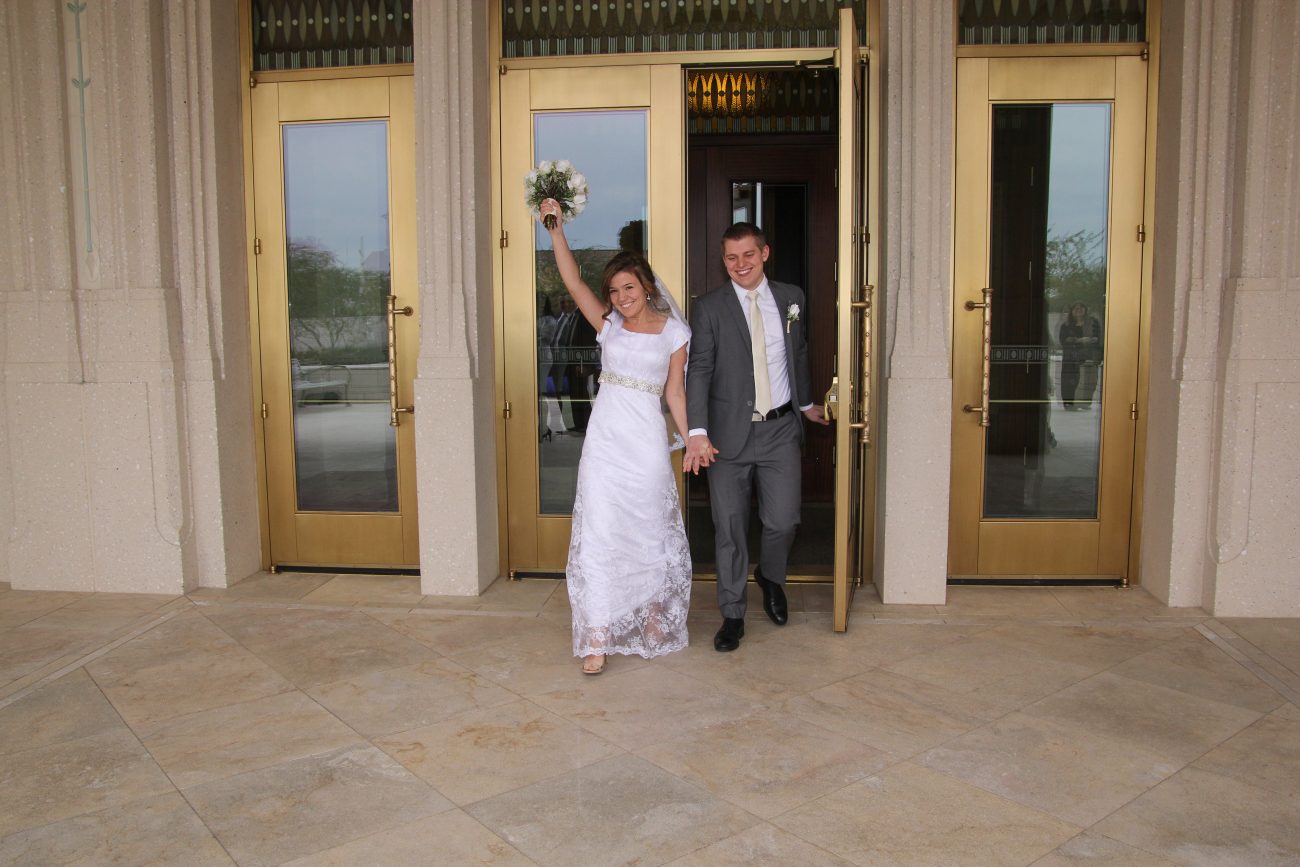 Bride holding flowers high after the wedding at the Phoenix Arizona Temple.