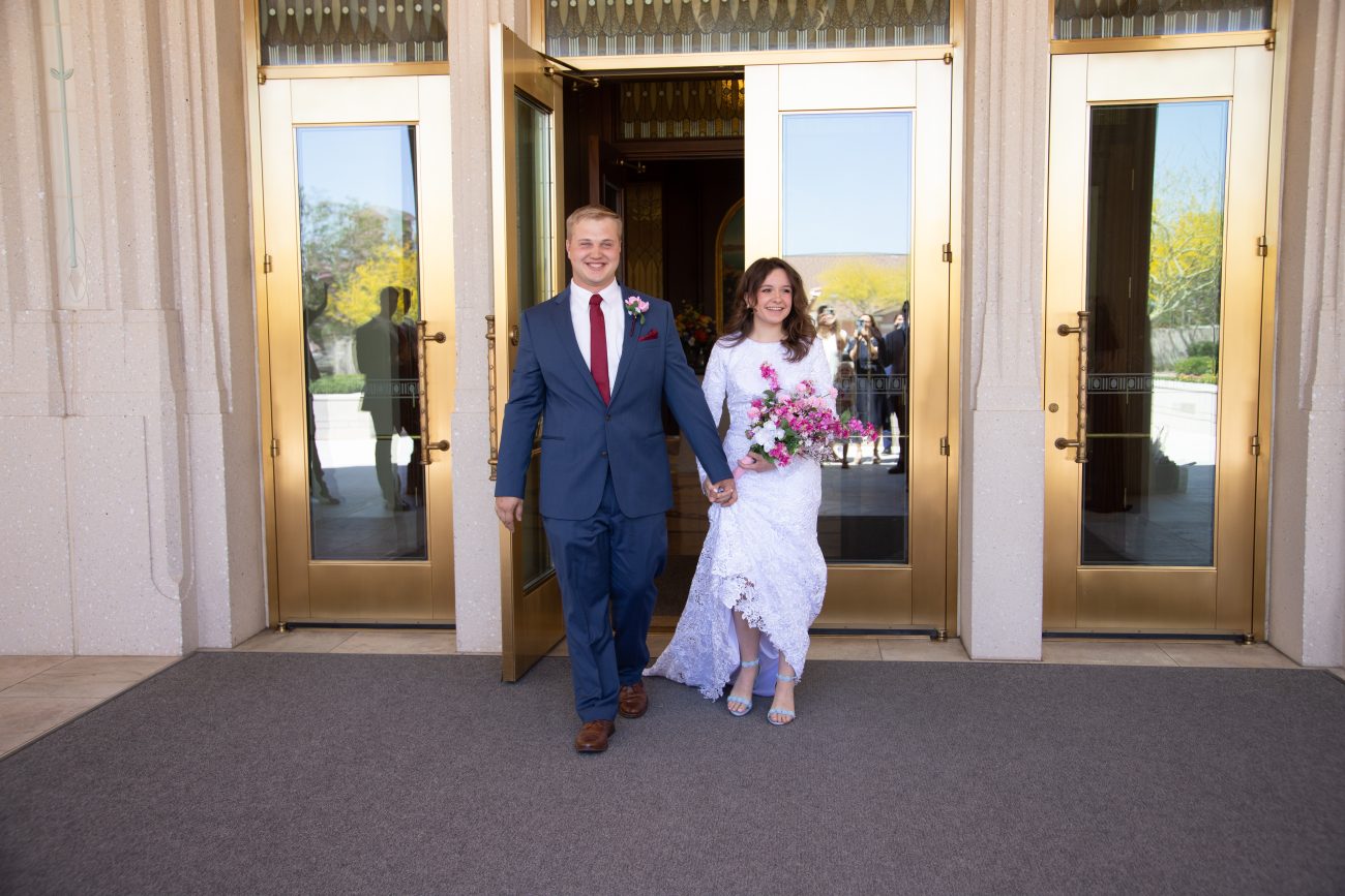 Bride and groom smiling as they exit the Phoenix Temple after their wedding.