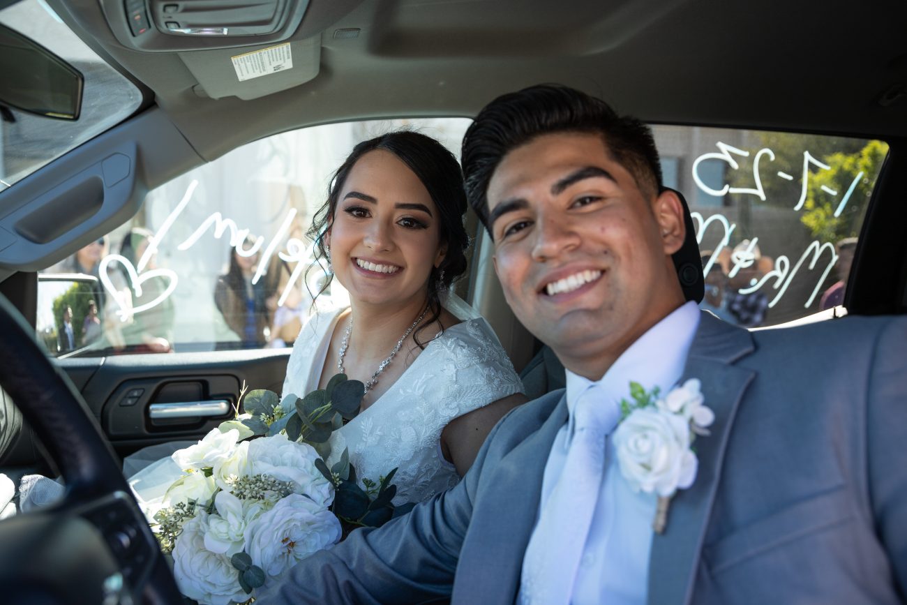 Bride and groom in their truck driving away from the Tucson Temple after the wedding.