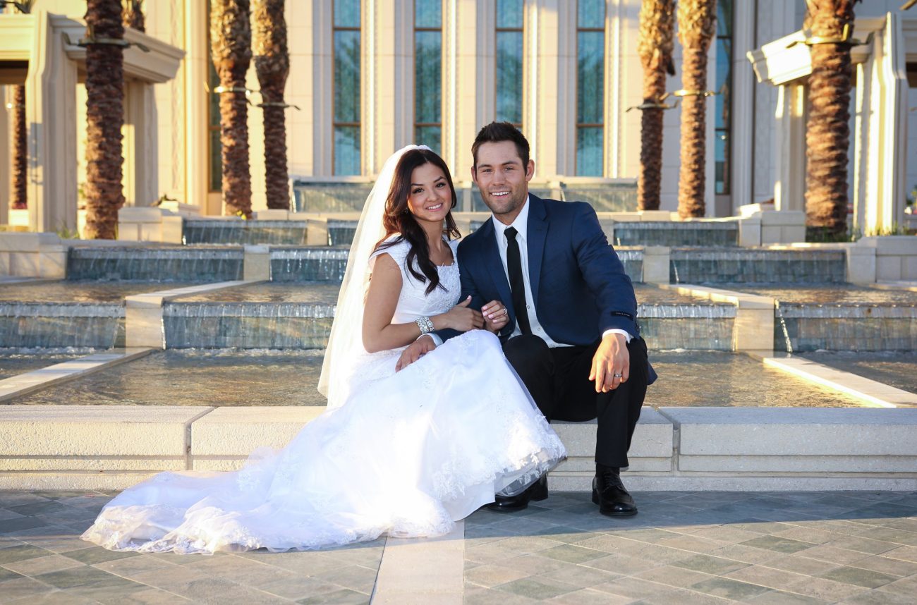 Bride and groom seated by the water feature at the Gilbert Arizona Temple