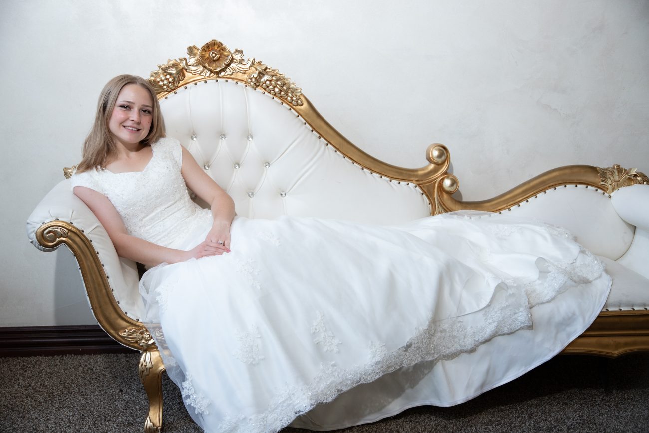 Bride posing on a large white chaise lounge at her LDS Wedding reception in Phoenix Arizona.